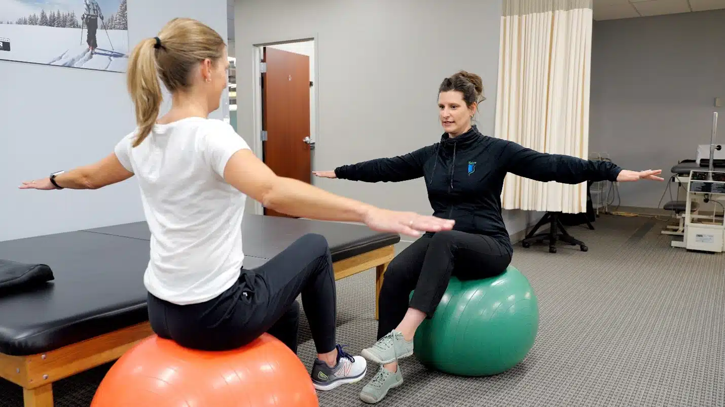 a clinician assisting someone on an exercise ball cognitive behavioral coaching can help with pain management