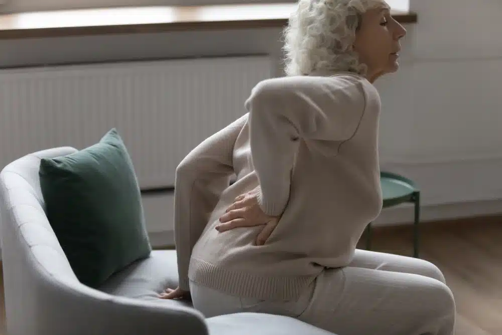 Woman experiencing low back pain when transitioning from sitting to standing