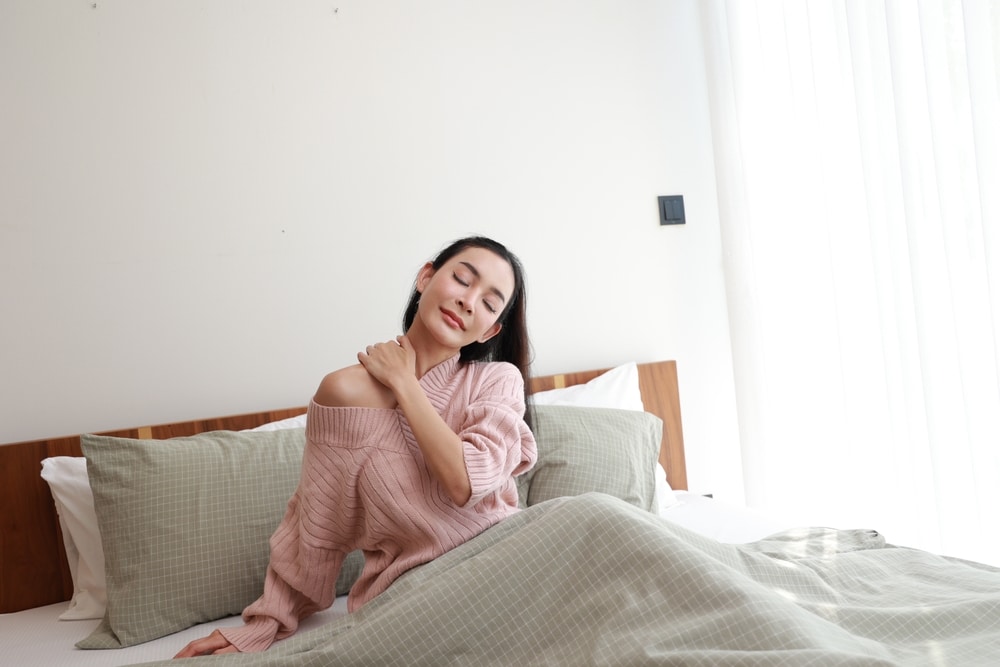 Woman stretching neck in bed