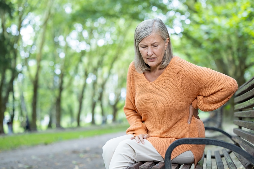 Woman on bench in spring with back pain